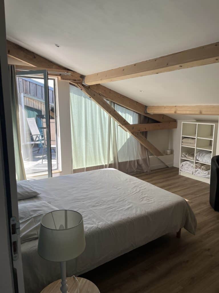 Ancienne cave voûtée transformée en chambre d'hôtel avec poutres apparentes.