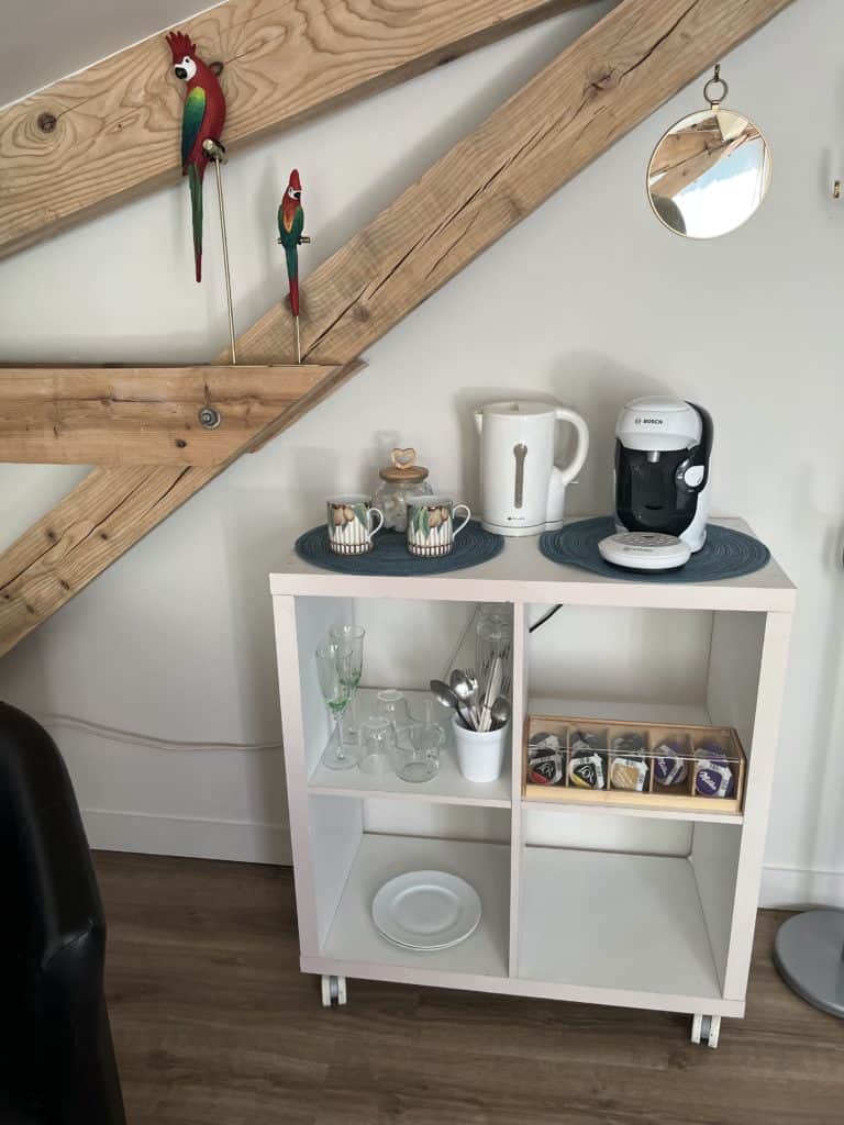 Paravent Les Voûtes de Villebourbon, bar convivial avec machine à café, vaisselle et décoration intérieure chaleureuse.