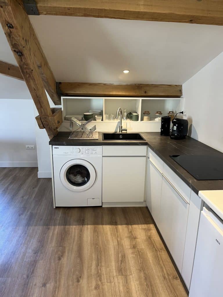 - Alt : Coin cuisine moderne dans les Voûtes de Villebourbon avec lave-linge intégré.